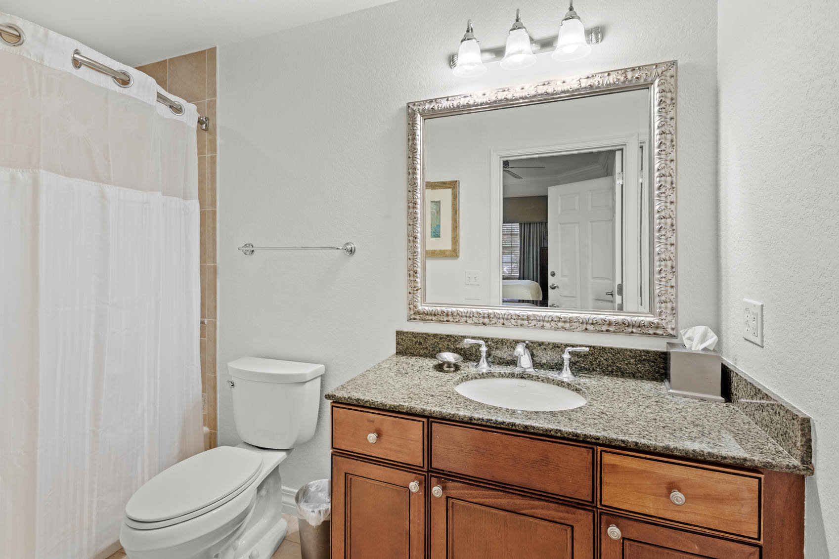 bathrom with white shower curtain and dark cabinet